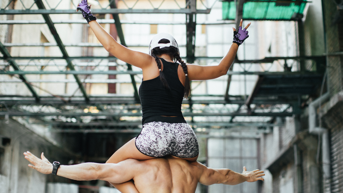 Woman in a gym on the shoulders of a fit man