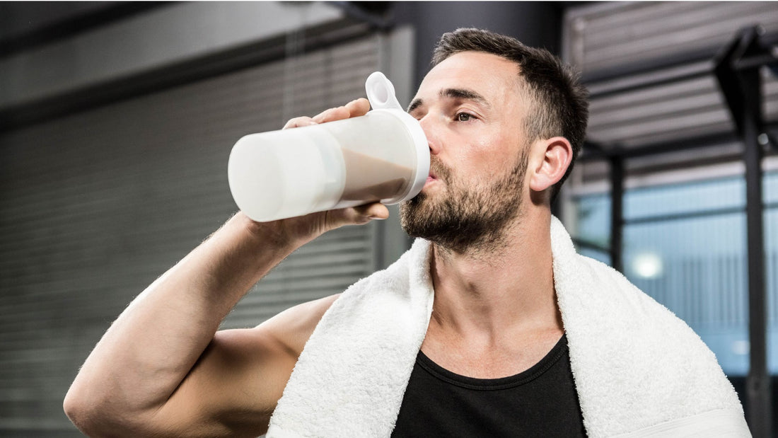 A man sits post-workout, savoring a protein shake with a satisfied expression. His relaxed demeanor reflects the rejuvenation and replenishment that follows physical exertion, promoting recovery and muscle growth