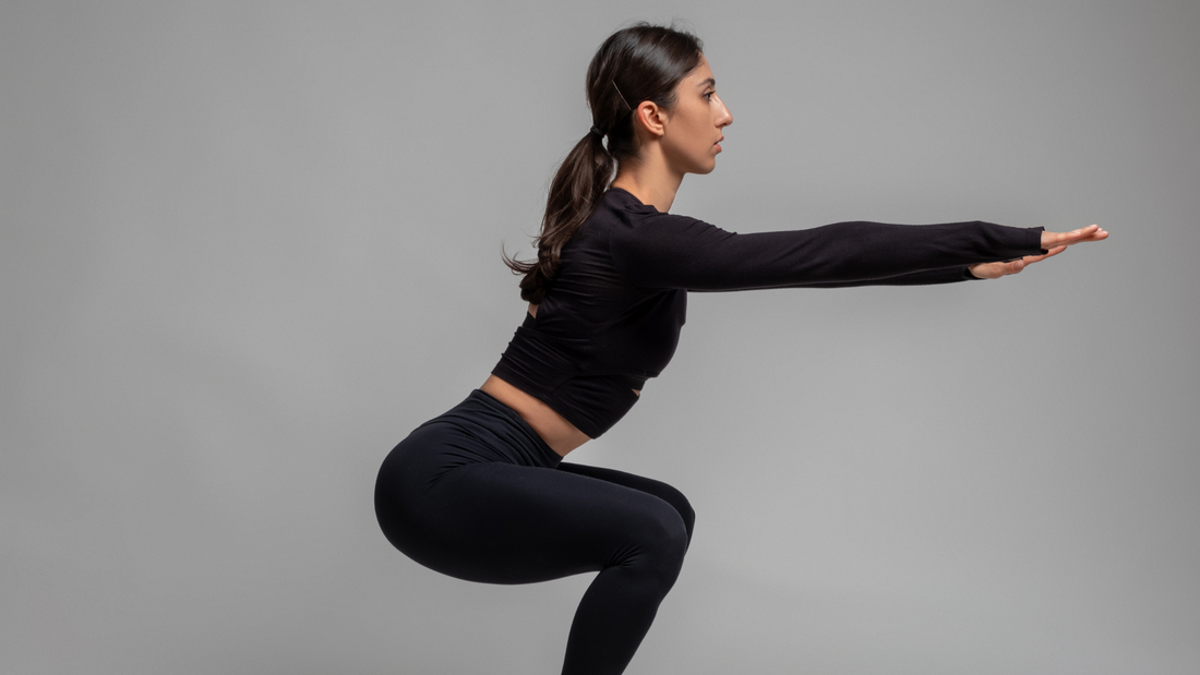 a woman doing a squat while wearing black shirt and leggings